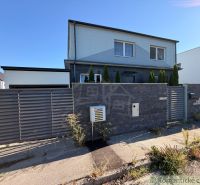A family house in Komárno with a modern fence and landscaping with plants at the entrance.