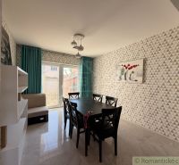 A dining room in a family house with geometric wallpaper, a black table, and turquoise curtains.