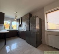 A kitchen in a family house with light walls and dark furniture.