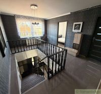 A staircase with black railings in a family house, with a view from the window.