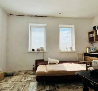 A room in a family house with a kitchen unit, wooden decor flooring, and a sofa.