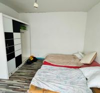 Bedroom with a bed, wardrobe, and wooden decor flooring in a family house.