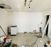 A room in a family house with clutter, a stove, and repairs on the ceiling and floor.