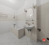 Bathroom with a bathtub and a sink in a 2-room apartment, light tiles.
