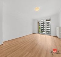 A bright room with wood-patterned flooring and balcony doors in a 2-room apartment.