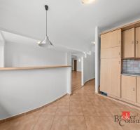 A kitchen in a 2-room apartment with light tiles and wooden decor cabinets.