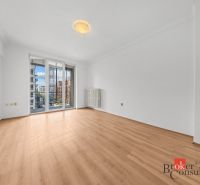 A bright room in a 2-room apartment with a wooden decor floor and balcony doors.
