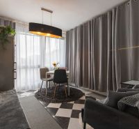 Living room in a two-room apartment with a dining table and gray curtains.