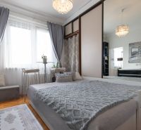Bedroom in a 2-room apartment with a bed, mirrored wardrobe, and floor with wood decor.