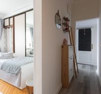 Two-room apartment with a bed, wardrobe, mirrors, and a floor with a wooden decor.