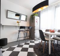 Dining area in a 2-room apartment with a dining table and black chairs.