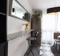 A kitchen with a dining table, a mirror, and high chairs in a 2-room apartment.