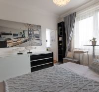Bedroom in a 2-room apartment with decorative pillows, a painting, and a large window.