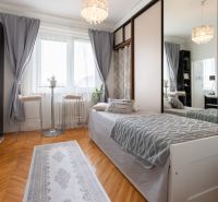 A room in a 2-room apartment with a bed, a mirrored wardrobe, and a floor with a wooden decor.