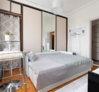 Bright room with a bed, wardrobe with mirrored doors, and a wooden decor floor.