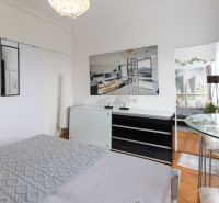 A bedroom in a two-room apartment with a wooden decor floor and elegant furniture.