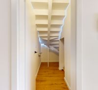 A narrow room with a wooden decor floor and a staircase in a 5 or more bedroom apartment.