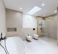A spacious bathroom with a freestanding bathtub and a clear shower enclosure in a multi-room apartment.