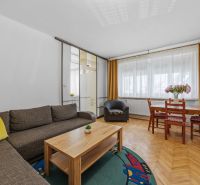 Living room in a two-room apartment with a wooden decor floor and a comfortable sofa.