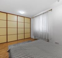 Bedroom in a 2-room apartment with wood-patterned flooring, a wardrobe, and curtains.