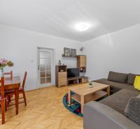 A bright living room in a two-room apartment with a wooden-patterned floor and a comfortable sofa.