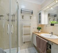 Bathroom with a spacious shower, sink, and light tiles in a 2-room apartment.