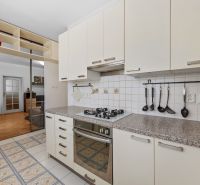 A kitchen in a 2-room apartment with a gas stove, a mirrored wardrobe, and tiles.