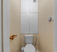 A bathroom with tiles and a white shelf in a 2-room apartment.