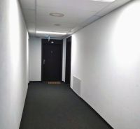 A hallway with white walls and a gray carpet leading to a door.