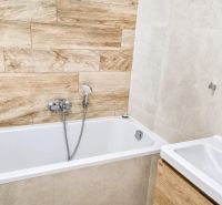 Bathroom with a bathtub and shower, 2-room apartment, tiles with wood decor.