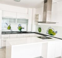 A kitchen in a 2-room apartment with white furniture and glass tiles.
