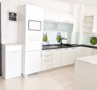 Seamless kitchen in a 2-room apartment with white cabinets and green fruit decor.
