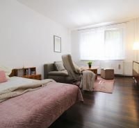 Interior of a 1-room apartment with a bed, an armchair, and a wooden decor floor.