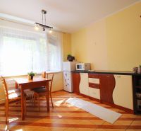 A kitchen in a studio apartment with a dining table and a wood-patterned floor.