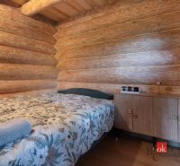 A bedroom in a family house with wooden walls, a patterned bed, and a cabinet.