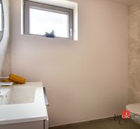 A bathroom in a family house with light tiles, a sink, and a toilet.