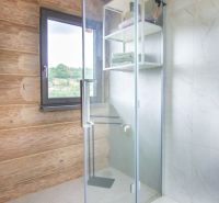Shower enclosure with glass doors and wooden decor in a family house.