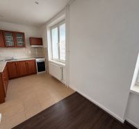 A kitchen in a 2-room apartment with wooden decor and tiled flooring.