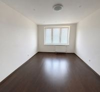 A room in a 2-room apartment with a wooden decor floor and three windows.