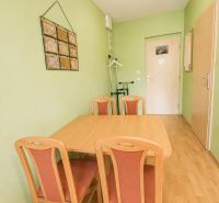 A dining room with a wooden table and chairs, and a floor with a wooden decor.
