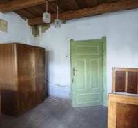 A room in a family house with a wooden ceiling, green doors, and furniture.