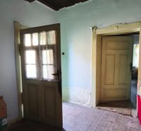Interior of a family house with a wooden ceiling, doors, and an older floor.
