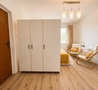 Interior of a 1-room apartment with a white wardrobe and a wooden decor floor.