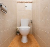 Toilet in the bathroom with cream tiles in a studio apartment.
