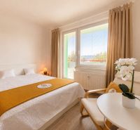 Bright bedroom with a large bed and a flower, studio apartment.