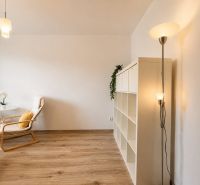 A room with a wooden decor floor, a white shelf, and a comfortable armchair.