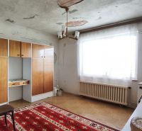 The interior of a family house with retro furniture, a red carpet, and a large window.