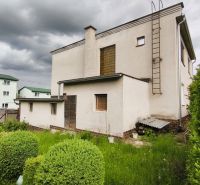A family house in Nenince with a lawn and shrubs, under a cloudy sky.
