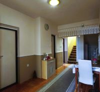 A hallway in a family house with a carpeted staircase, a table, and a floor with a wooden decor.