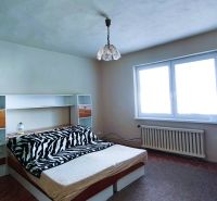 Bedroom in a family house with a bed, shelves, and a large window.